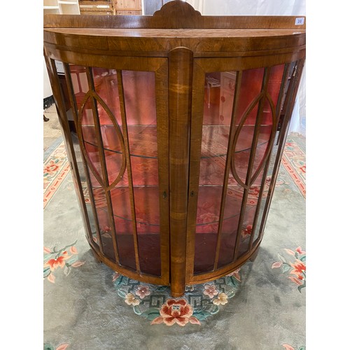 30 - A walnut veneered half round display cabinet with low raised back, fitted two glass doors and sides,... 