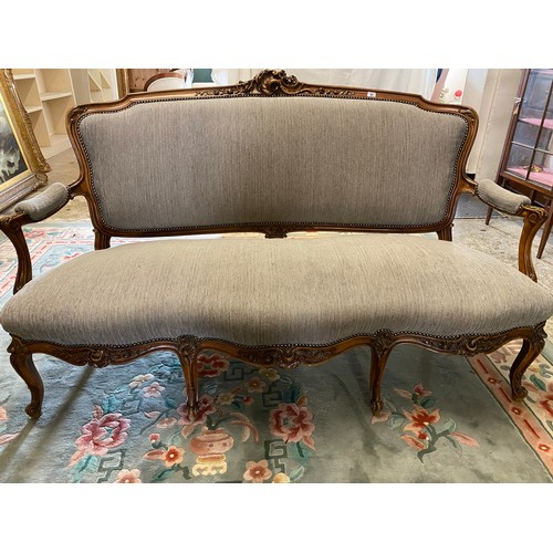 31 - A French style settee with flower carved frame, upholstered seat, back and armpads, on cabriole legs