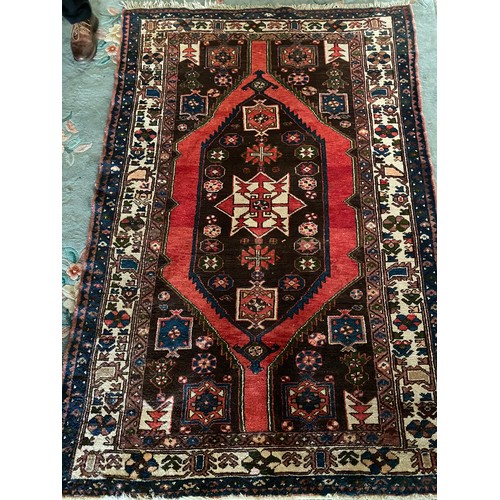 3 - An Eastern rug with lozenge centre in red, green, black and orange within red, black and grey stylis... 