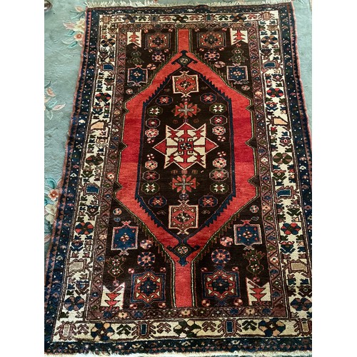 3 - An Eastern rug with lozenge centre in red, green, black and orange within red, black and grey stylis... 