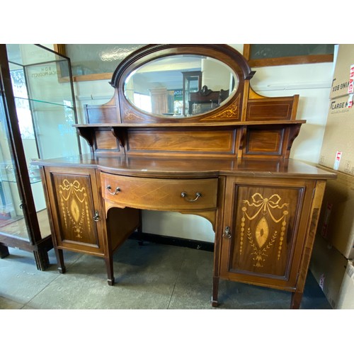 25 - An Edwardian mahogany and inlaid sideboard, the raised back fitted oval bevelled mirror, the base fi... 