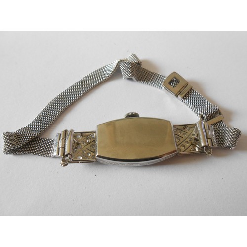 216 - A lady's Art Deco cocktail watch in a platinum case with diamond set bezel and shoulders, on a 9ct. ... 