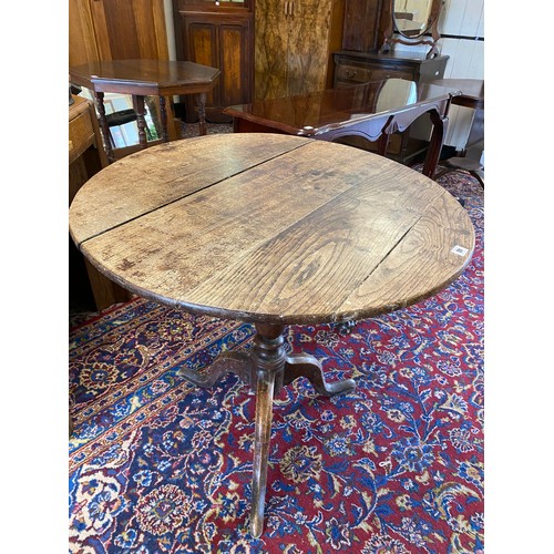 46 - A Georgian oak table with circular hinged top, on three downswept legs and pad feet - 31in. dia., a ... 