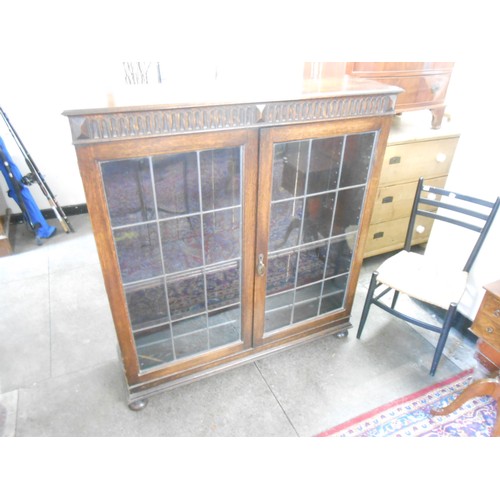 73 - An oak bookcase fitted two leaded glass doors, on bun feet - 48in. wide