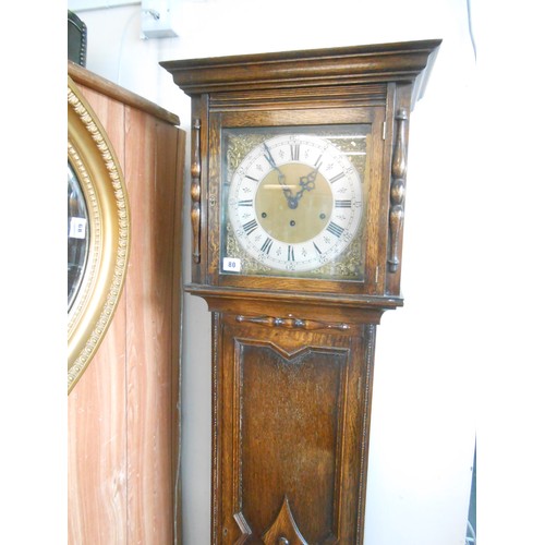 80 - A grandmother clock with brass dial, silvered chapter ring, in an oak case with panelled door and ba... 