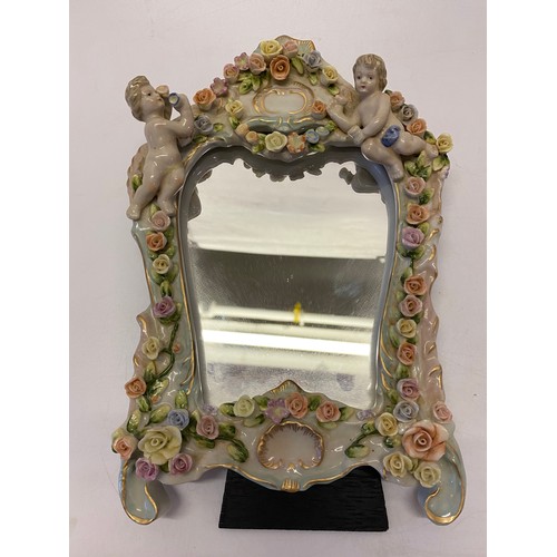 154 - A Continental mirror with easel back, the front with applied decoration of cupids and flower scrolls... 