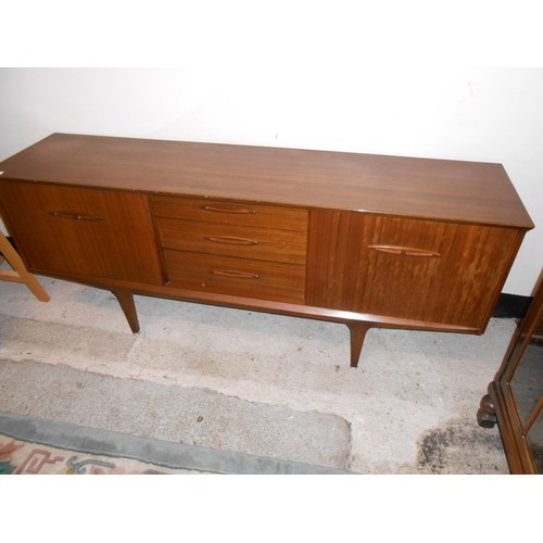 74 - A teak sideboard fitted three centre drawers flanked by sliding doors - 72in. wide