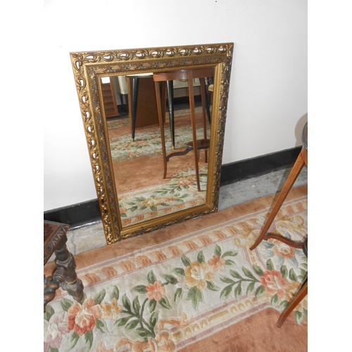 69 - A wall mirror in a decorative gilt frame - 52in. x 38in., a bevelled wall mirror in a gilt frame, a ... 