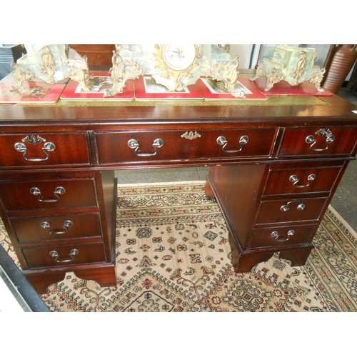 82 - A reproduction mahogany desk, the top inset green and gilt tooled leather top, fitted three frieze d... 