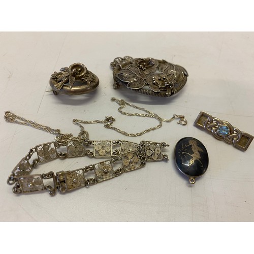 253 - A large silver coloured metal wirework brooch decorated flowers and leaves, a silver coloured metal ... 