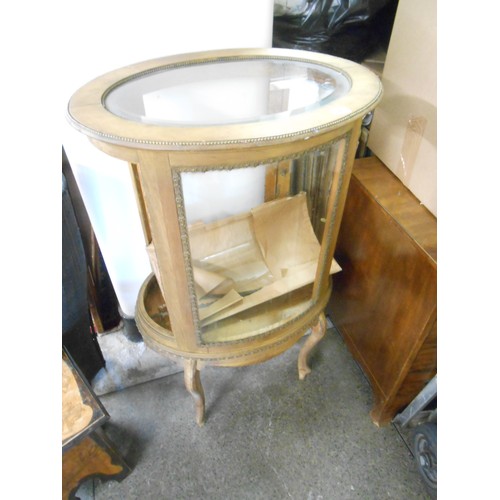 91 - An oval walnut finished bijouterie cabinet with glass top, door and sides, on slender legs - 25in. w... 