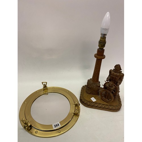 304 - A carved oak tablelamp base in the form of a sailor and lighthouse and a mirror in the form of a bra... 