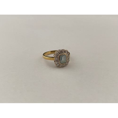 196 - A lady's ring set centre pale blue coloured stone surrounded by diamonds, on an 18ct. gold shank