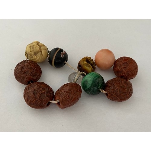 201 - A bracelet with five carved nut beads, malachite bead, glass bead, Japanese ivory bead in the form o... 