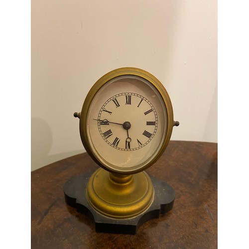 111 - A desk clock with cream enamel dial, in a gilt metal oval case, on shaped black marble base - 6in. h... 