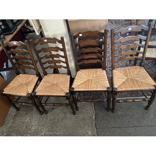 19 - A set of four stained as ash dining chairs with ladder backs and rush seats, on turned legs