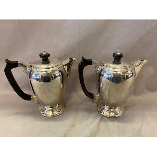 155 - A pair of Mappin and Webb silver hot water jugs with ebonised handles and knops, on circular bases -... 