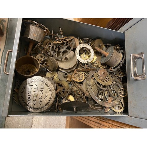 100 - A grey metal filing chest containing carriage clock balances, clock wheels, springs, orb finials, wa... 