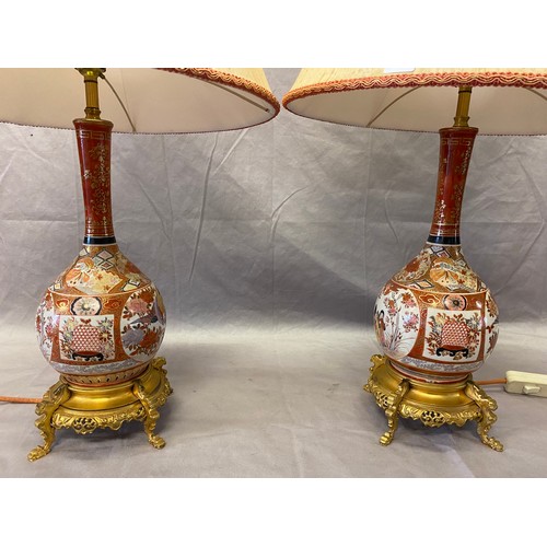 193 - A pair of Kutani bottle shaped vases decorated figures and flowers in reserves, on later ormolu base... 