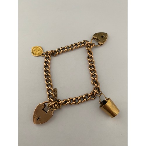 228 - A gold coloured metal bracelet hung with two 9ct. gold heart shaped padlocks, a 9ct. gold charm in t... 