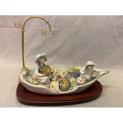 106 - A large Lladro group of two figures in a flower laden boat, on wooden stand - 17in. wide