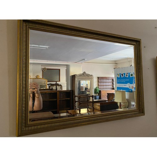 55 - A rectangular bevelled wall mirror in a gilt frame with fluted decoration - 38in. x 26in.