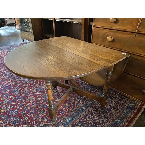 76 - A reproduction oak gateleg table fitted two rounded drop leaves, on turned and block legs - 36in. wi... 