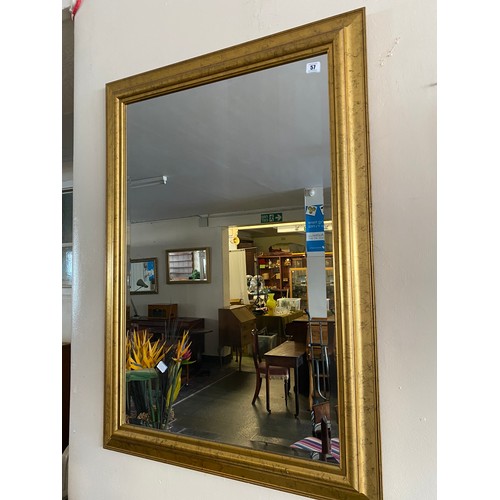 57 - A rectangular bevelled wall mirror in a gilt decorated frame - 42in. x 30in.