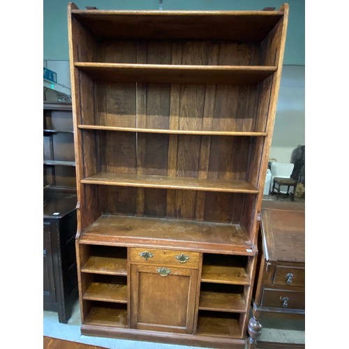 73 - An oak bookcase, the upper part fitted adjustable open shelves, the base with frieze drawer above hi... 