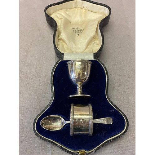 154 - A silver three piece christening set comprising:- egg cup, spoon and napkin ring, in fitted leather ... 