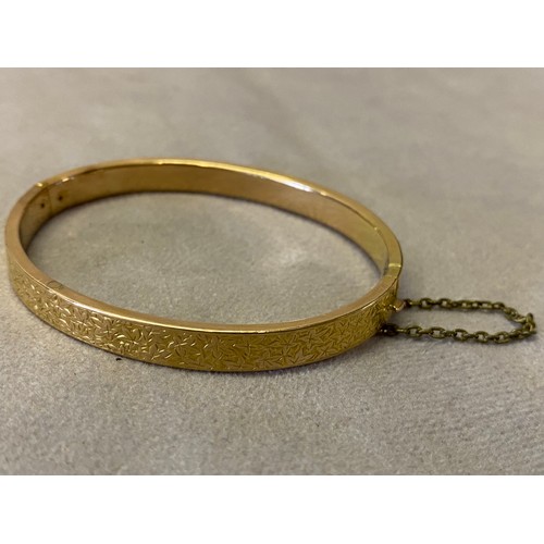 212 - A Victorian 15ct. gold bangle with engraved decoration of leaves to the top