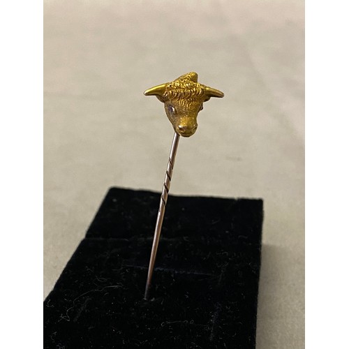 230 - A heavy gold coloured metal tie pin, the top in the form of a bull's head with ruby set eyes