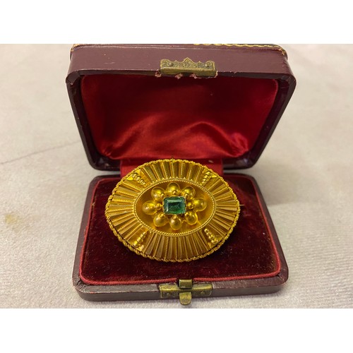 226 - A Victorian gold brooch of elliptical fluted form, the top set trap cut emerald, in fitted box