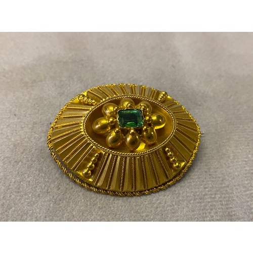 226 - A Victorian gold brooch of elliptical fluted form, the top set trap cut emerald, in fitted box