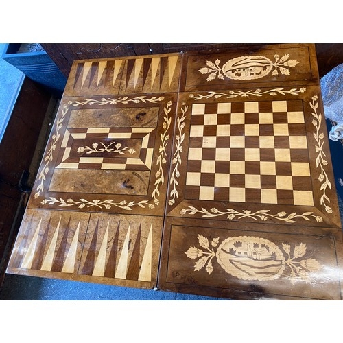 83 - An Italian walnut veneered and marquetry style games table with folding top enclosing chess and back... 