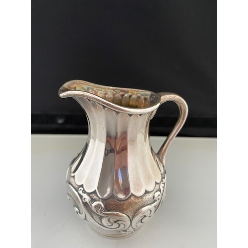 197 - A Victorian silver cream jug with hammered and leaf scroll decoration, panelled neck, on circular re... 