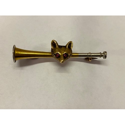 262 - An 18ct. gold bar brooch in the form of a hunting horn with fox surmount inset red stone set eyes