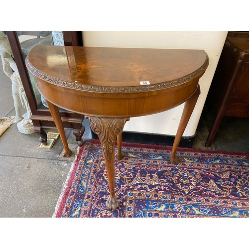 30 - A reproduction walnut and crossbanded card table with half round folding top, on cabriole legs termi... 