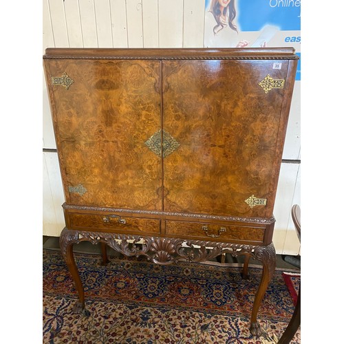 35 - A reproduction walnut cocktail cabinet fitted two doors, two drawers under, on cabriole legs