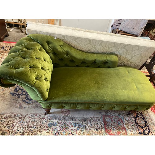 22 - A Victorian chaise longue upholstered in green velvet, on turned legs and castors