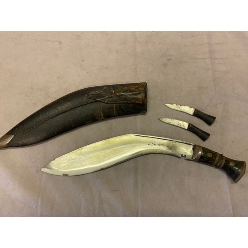 305 - A Kukri knife and two smaller knives with horn handles, in black leather scabbard