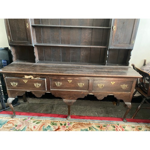 57 - An antique oak dresser, the upper part fitted shelves and cupboards, the base with shaped apron, fit... 