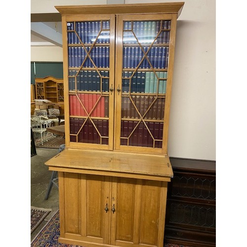 62 - A light oak bookcase, the upper part with two glass doors enclosing faux book fronts, the base fitte... 