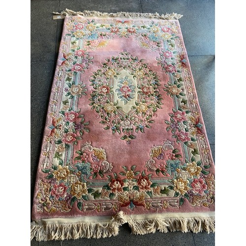 5 - A Chinese rug, pink field with repeating floral decoration, fringed - 51in. x 83in.