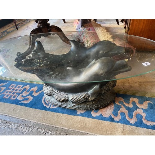 78 - A modern coffee table with oval glass top, resin dolphin base - 46in. wide