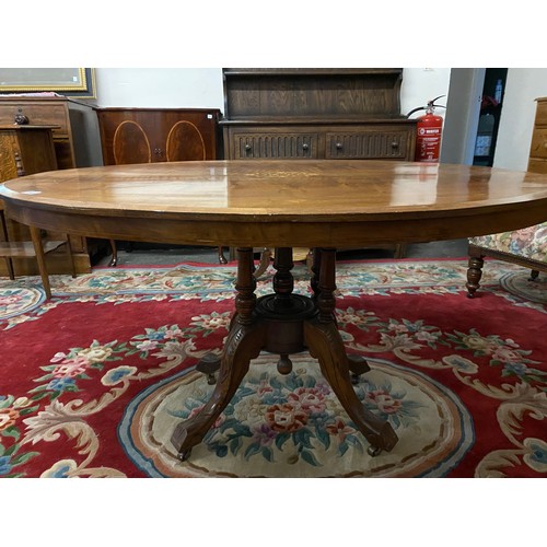 83 - A Victorian walnut loo table with oval top satinwood inlaid to the centre, on four cluster supports ... 