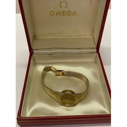 212 - A lady's Omega wristwatch with circular champagne dial, in a 9ct. gold case, on a 9ct. gold integral... 