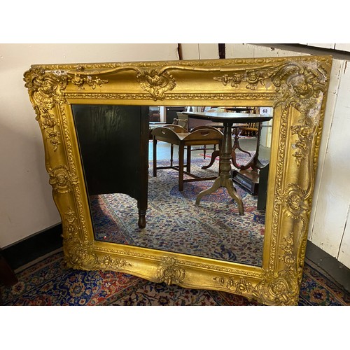 63 - A rectangular wall mirror in an ornate gilt plaster frame - 36in. x 40in.