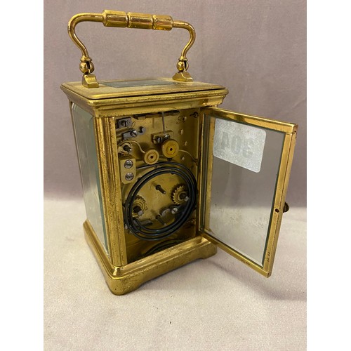 304 - A carriage clock, white enamel dial, alarm dial, striking movement on a gong, in a brass lacquered a... 