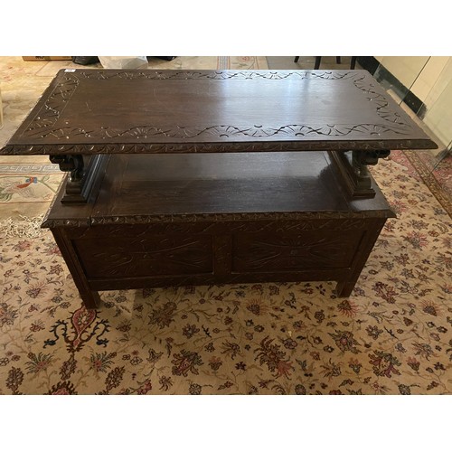 27 - An oak monks bench with hinged lid, lion form arm rests - 42in. wide